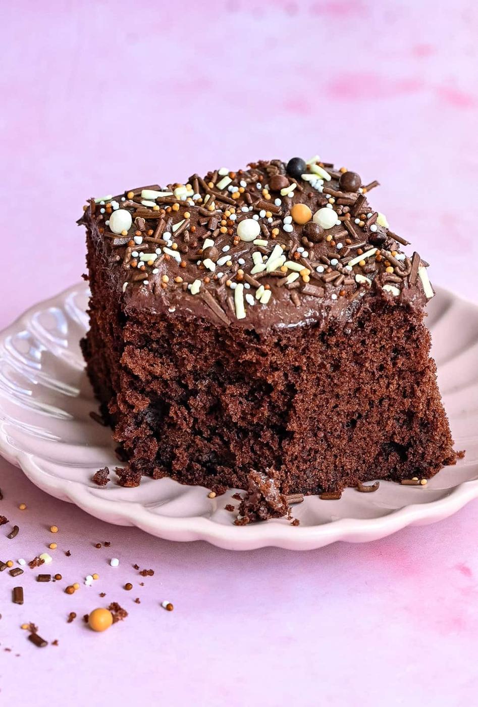 Slice of chocolate school cake on a pink plate, with bite taken out