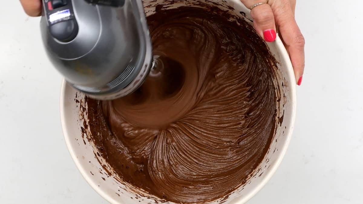 beating chocolate frosting with an electric hand mixer