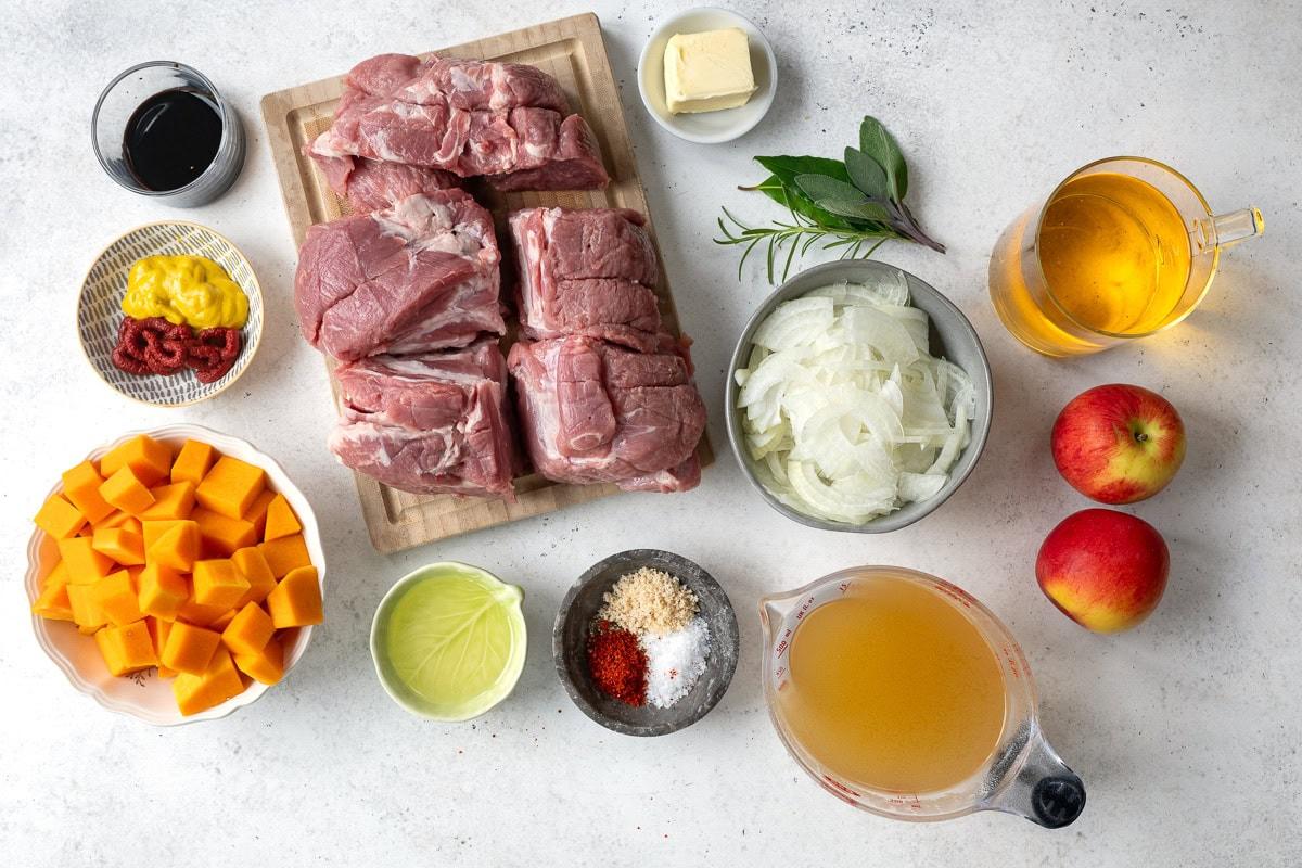 ingredients for cider braised pork shoulder laid out on a white background