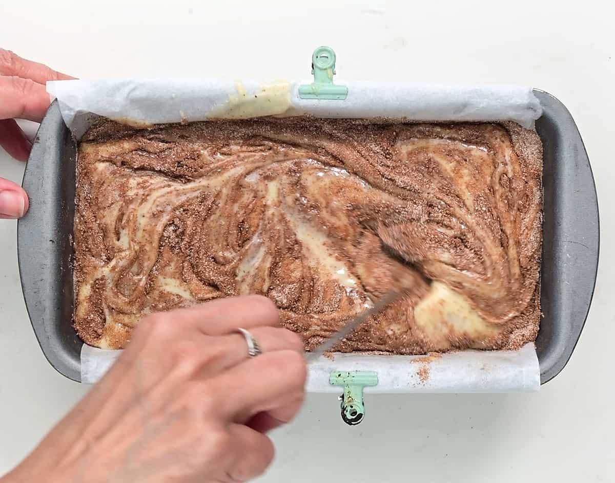 Swirling cinnamon bread batter in a lined loaf pan