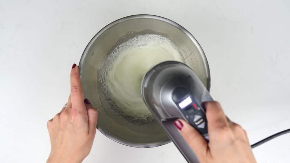 whisk egg whites with a hand mixer in a metal bowl
