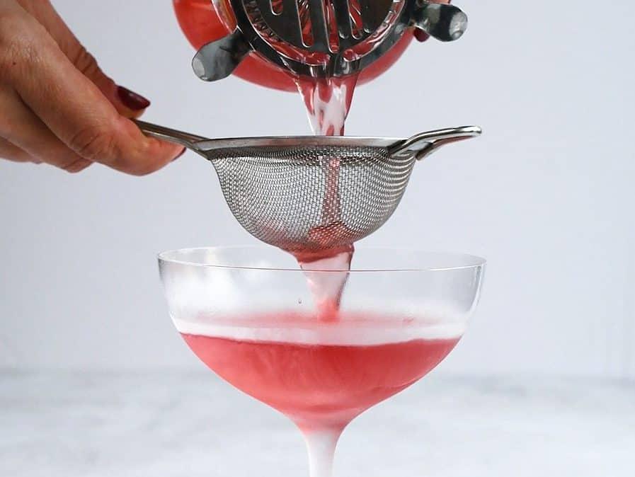 Straining a Cosmopolitan into chilled cocktail glass