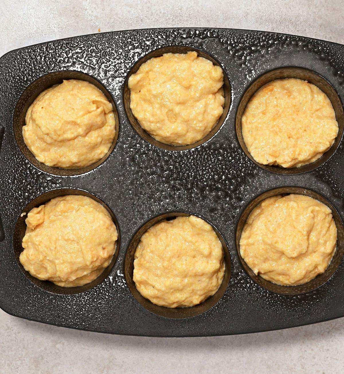 cornbread batter in a six hole muffin pan before baking