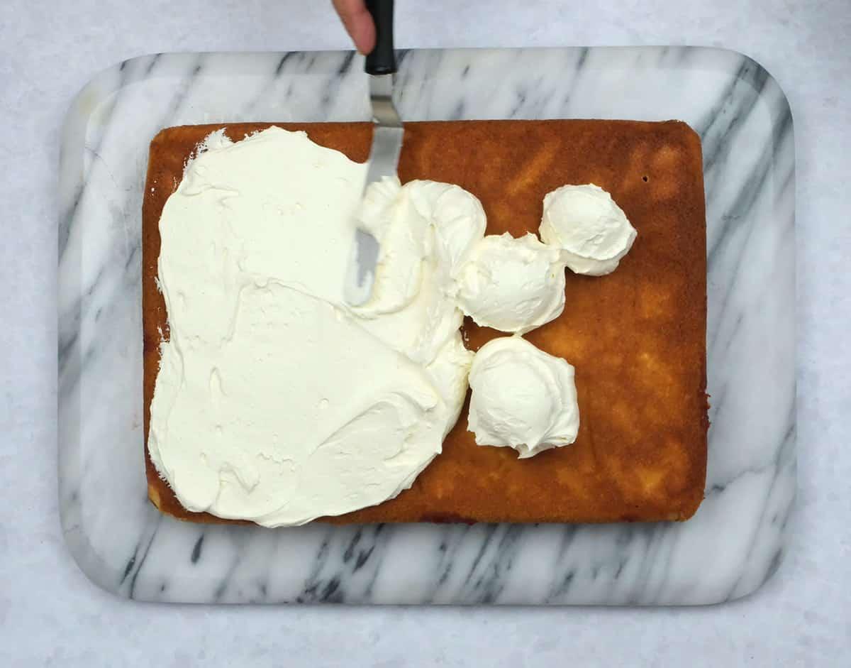 spreading whipped cream over cake