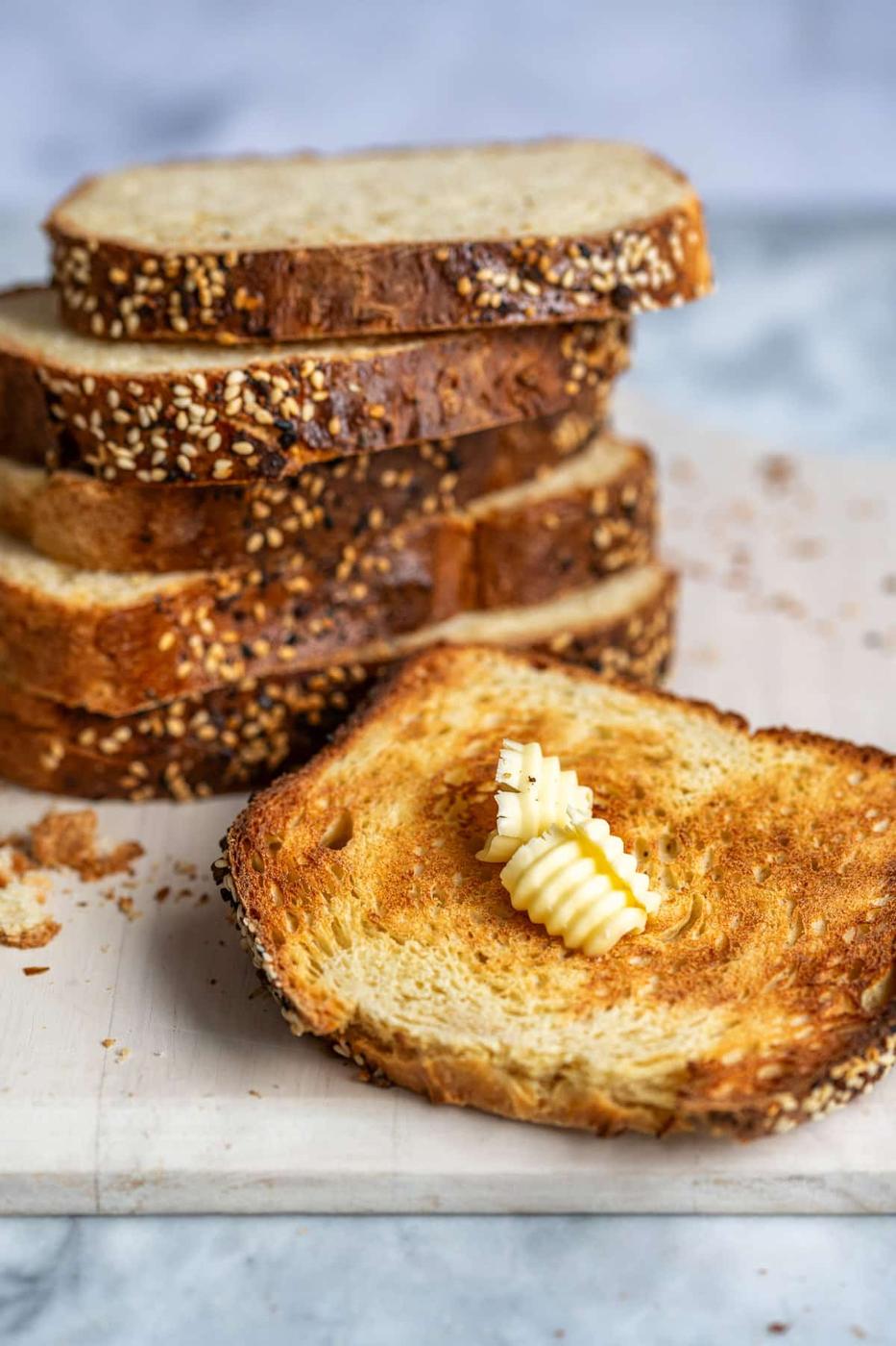 toasted slice of cottage cheese bread with butter, stack of bread slices behind it