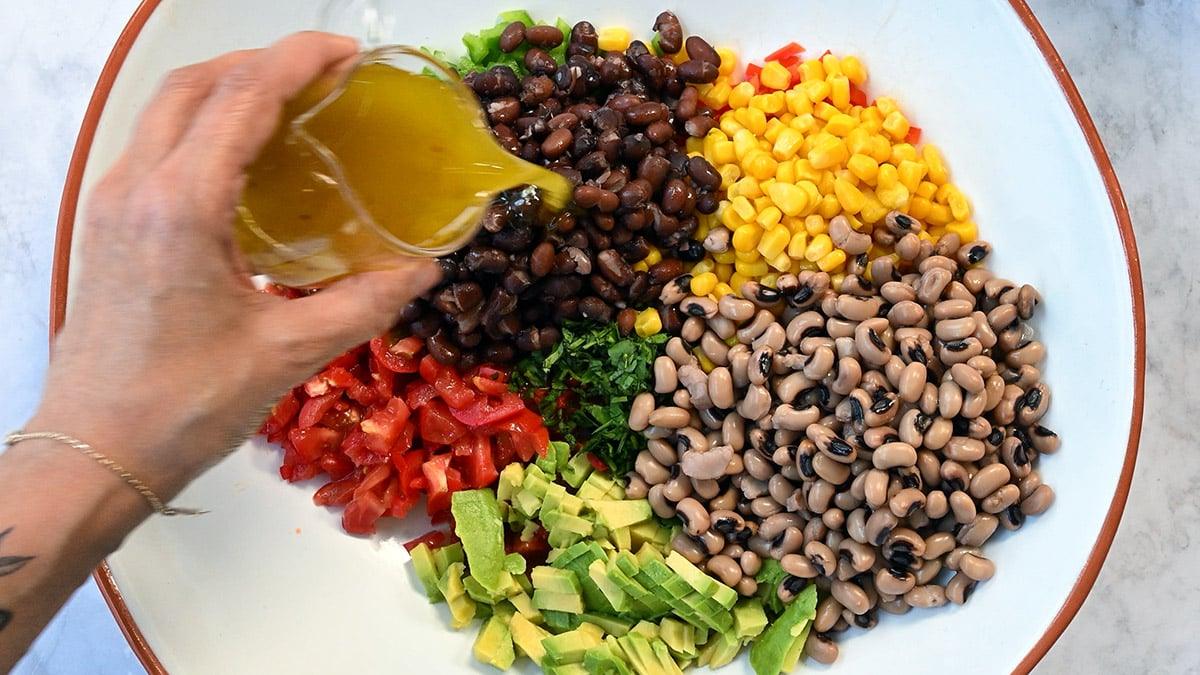 Extreme close up of dressing being added to Cowboy Caviar.