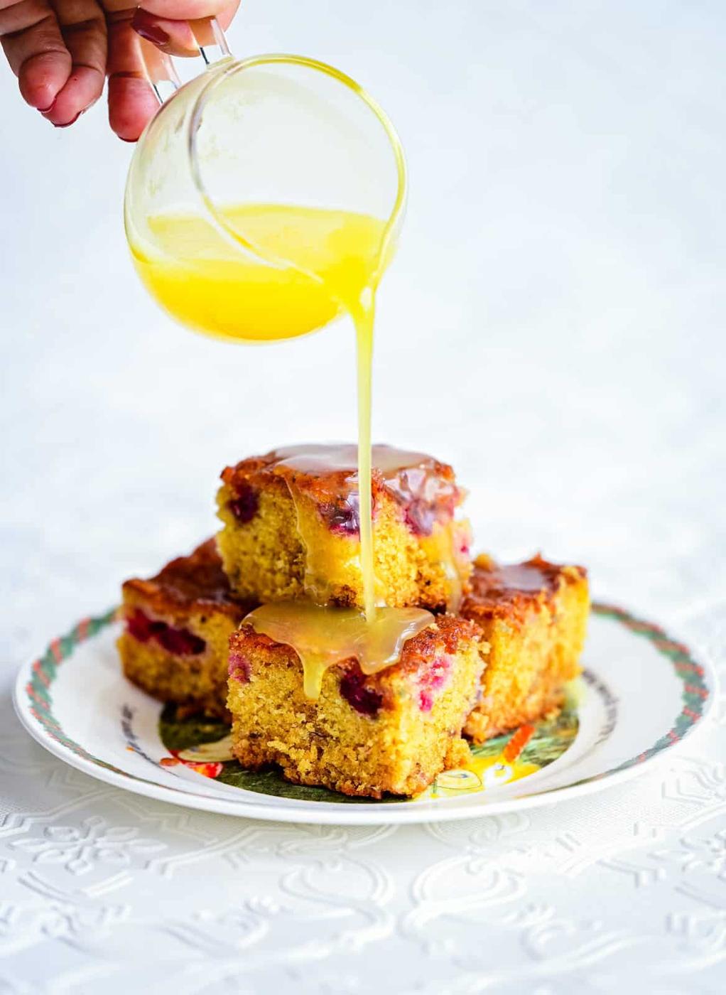 Pouring butter sauce over cranberry cake squares