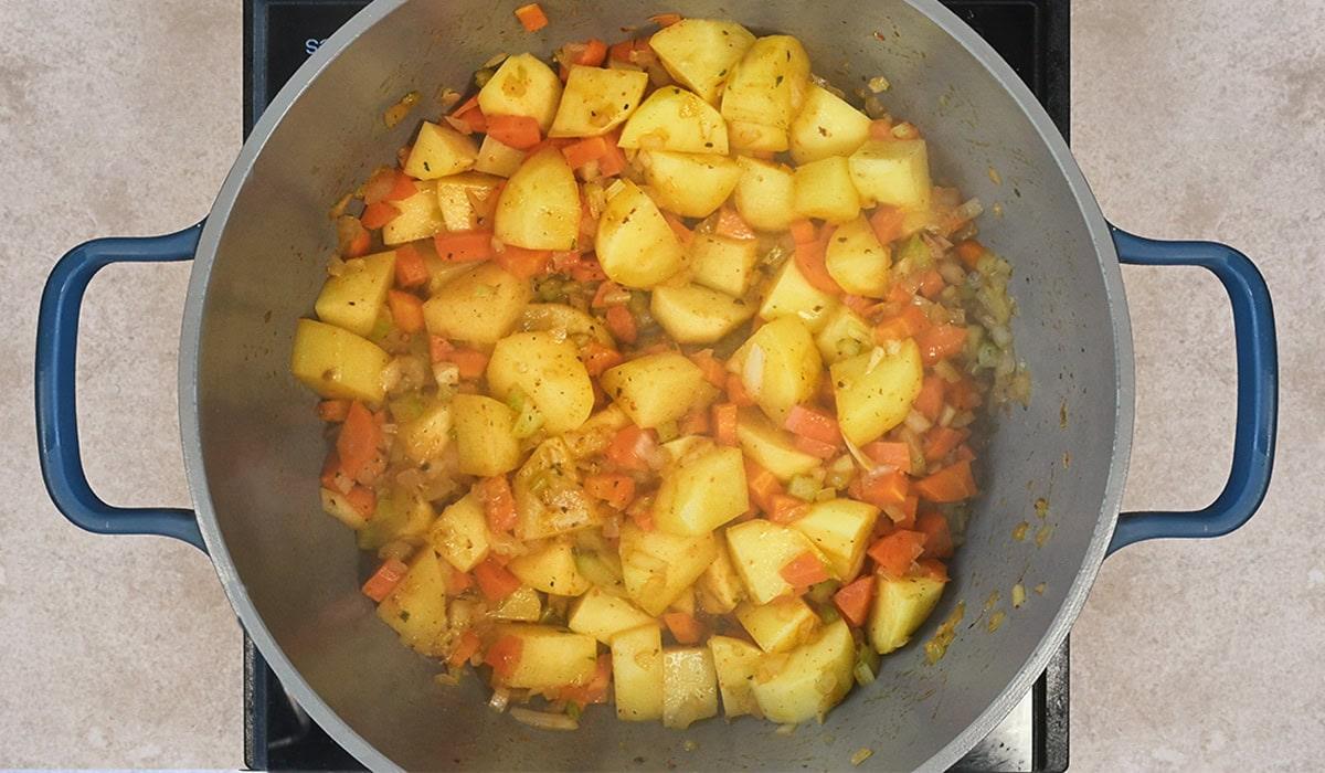 mirepoix and potatoes cooking for soup base in Dutch Oven