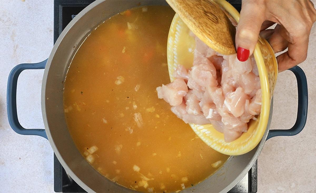 adding diced chicken to soup pot