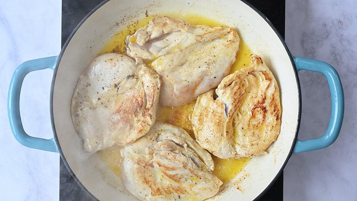 pan frying butterflied chicken breasts in a skillet