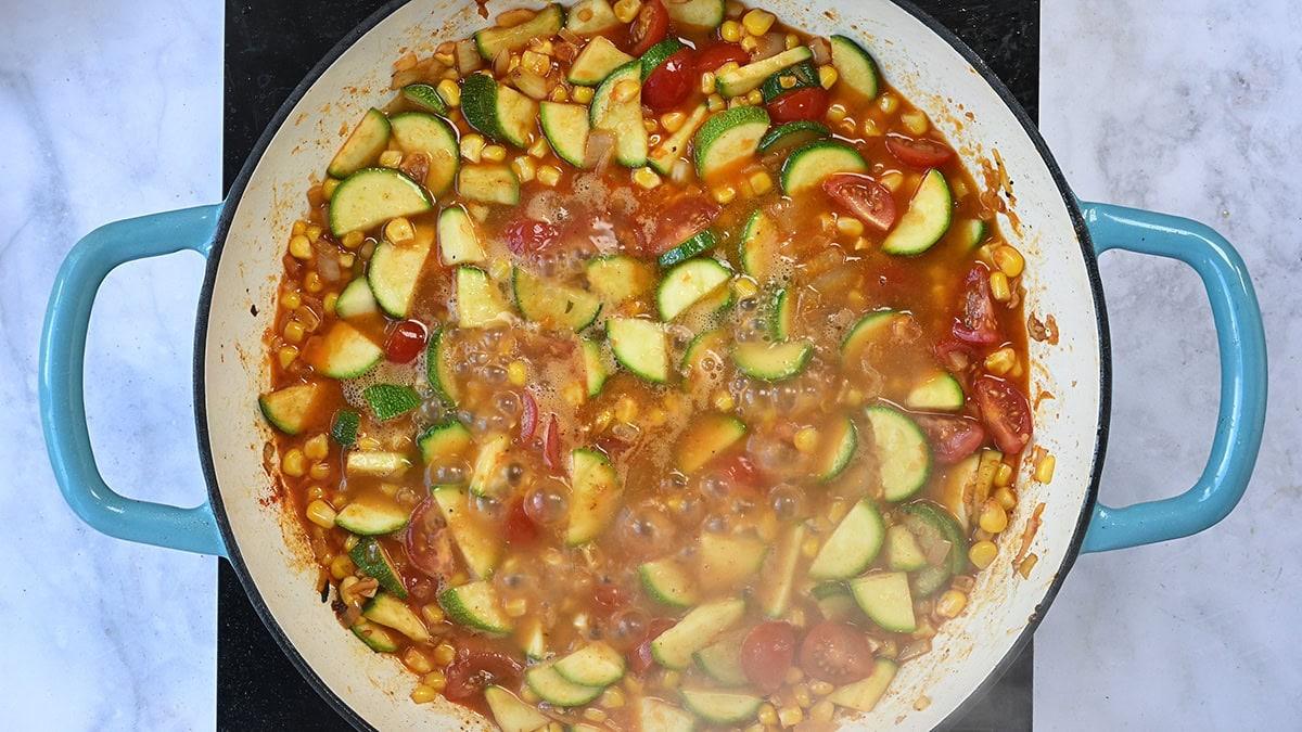 shallots, corn, zucchini and cherry tomatoes cooking in a skillet