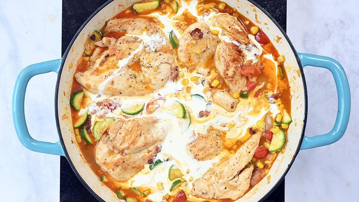 adding cream to a skillet of chicken