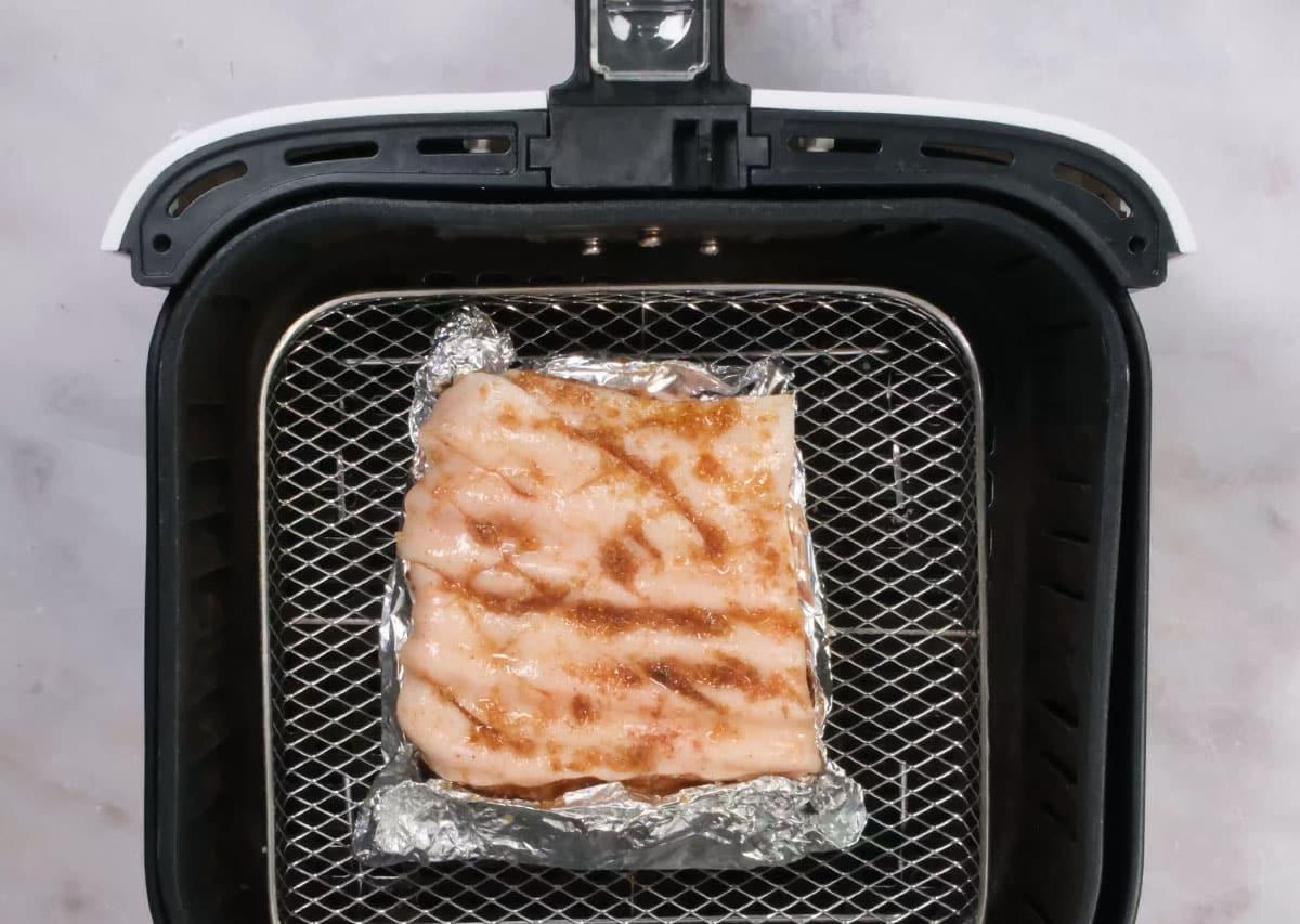 seasoned pork belly, flesj covered with foil, in air fryer basket
