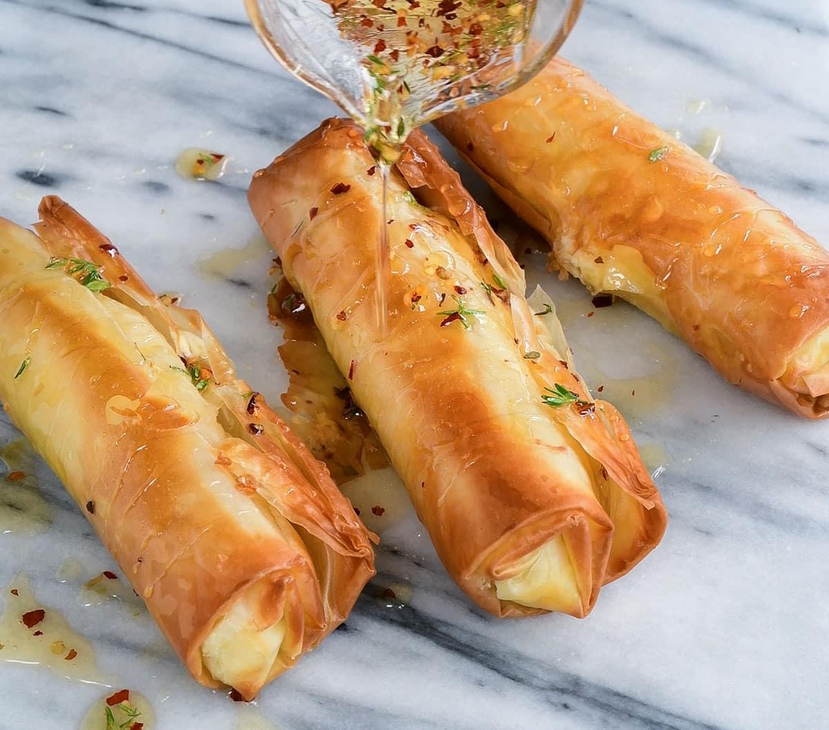 drizzling spicy honey over crispy feta rolls