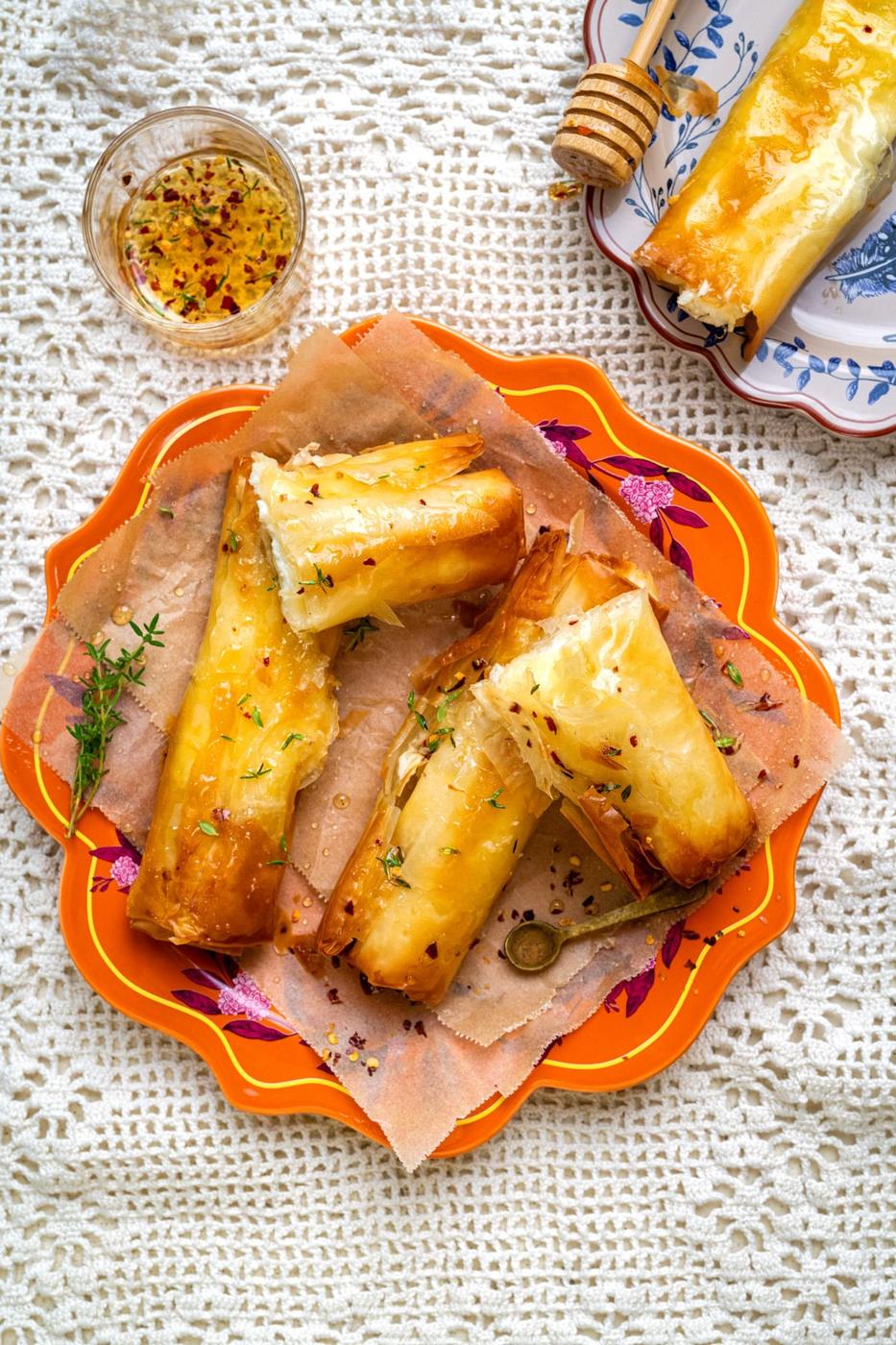 Phyllo feta parcels on an orange plate with honey dip on the side