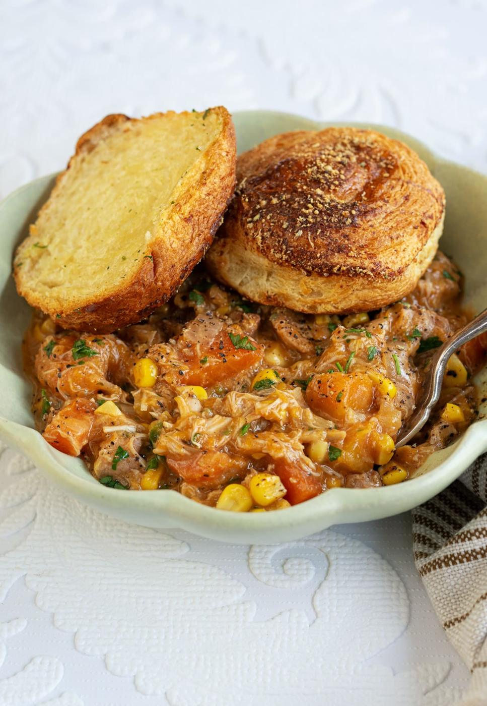 crock pot chicken pot pie served in a bowl topped with crescent rolls