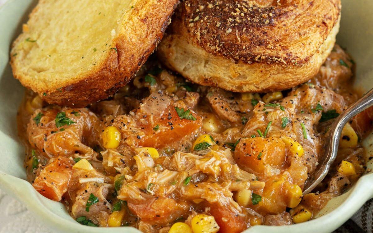 crock pot chicken pot pie served in a bowl topped with crescent rolls
