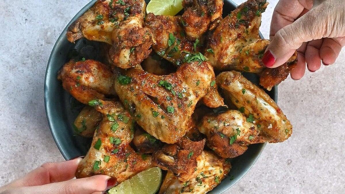 slow cooker chicken wings on a plate, hands reaching in to pick them