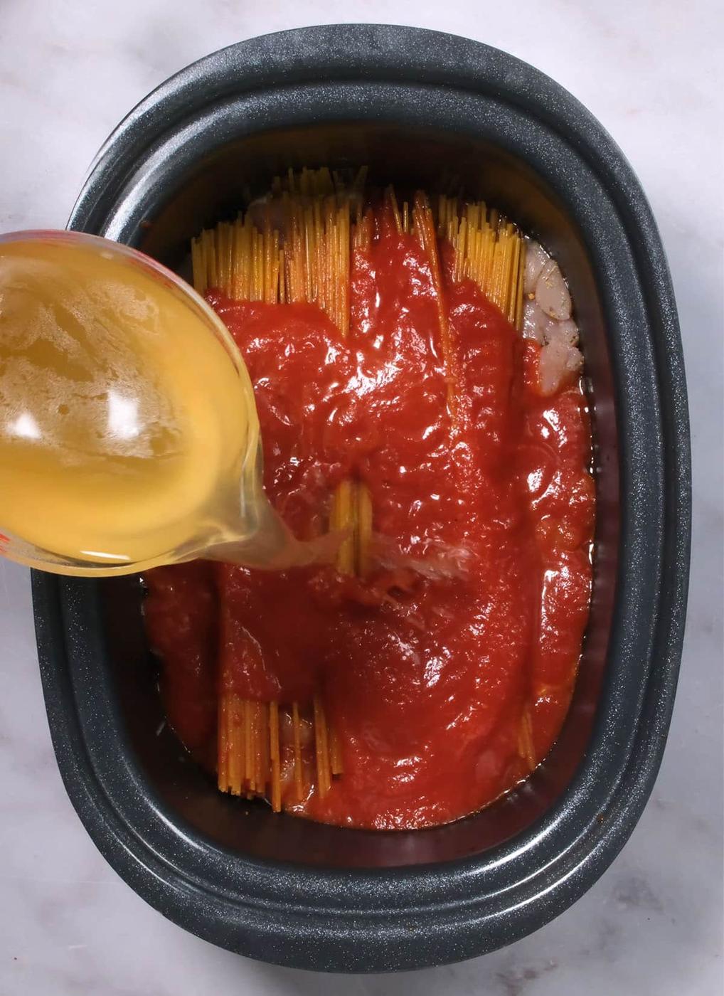 adding chicken broth to a slow cooker to make crockpot spaghetti