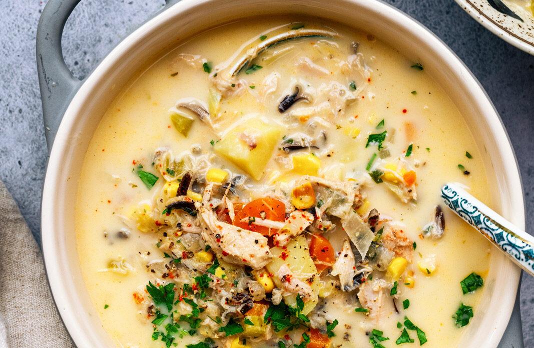 Overhead photo of crockpot turkey soup in a small ceramic pot, a bowl serving of the soup on the side.
