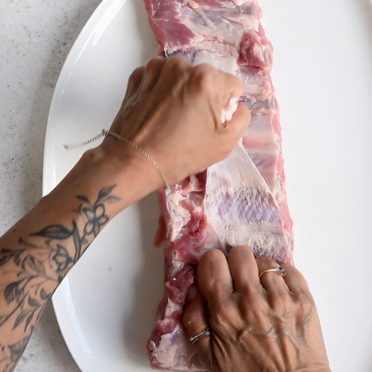 pulling the membrane off a rack of pork ribs
