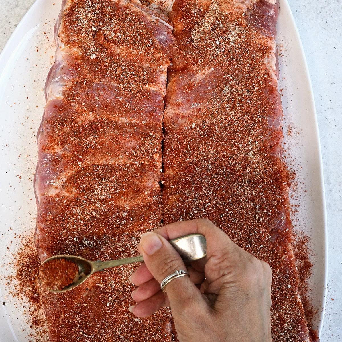 Covering pork rib racks with dry rub