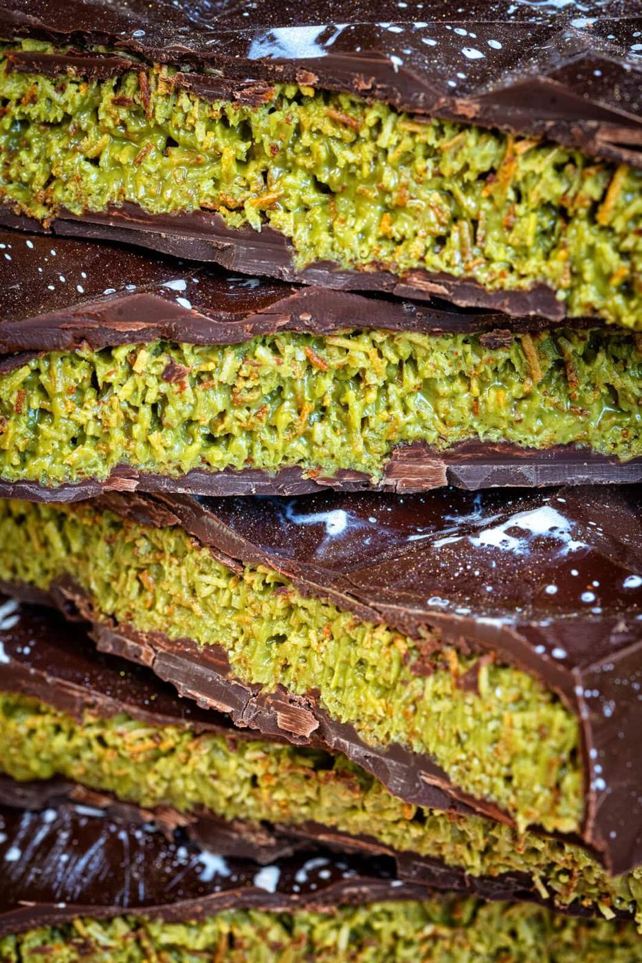 Close-up of several stacked slices of dark chocolate with a green pistachio, tahini and kataifi filling
