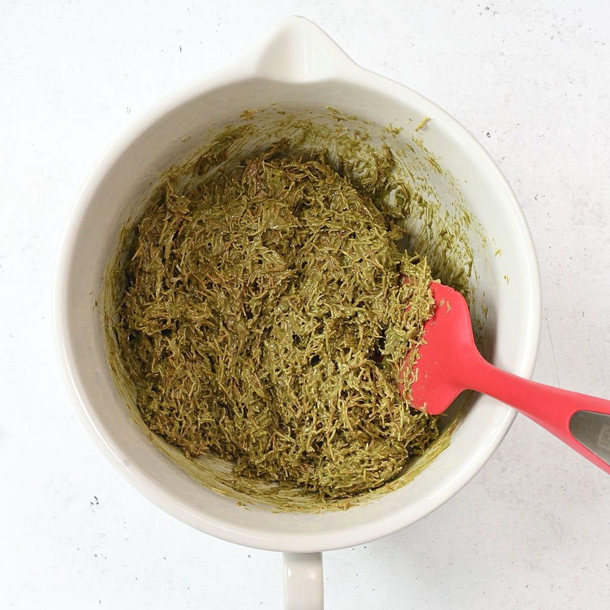 A white mixing bowl containing Dubai chocolate filling (pistachio cream, tahini and toasted kataifi)