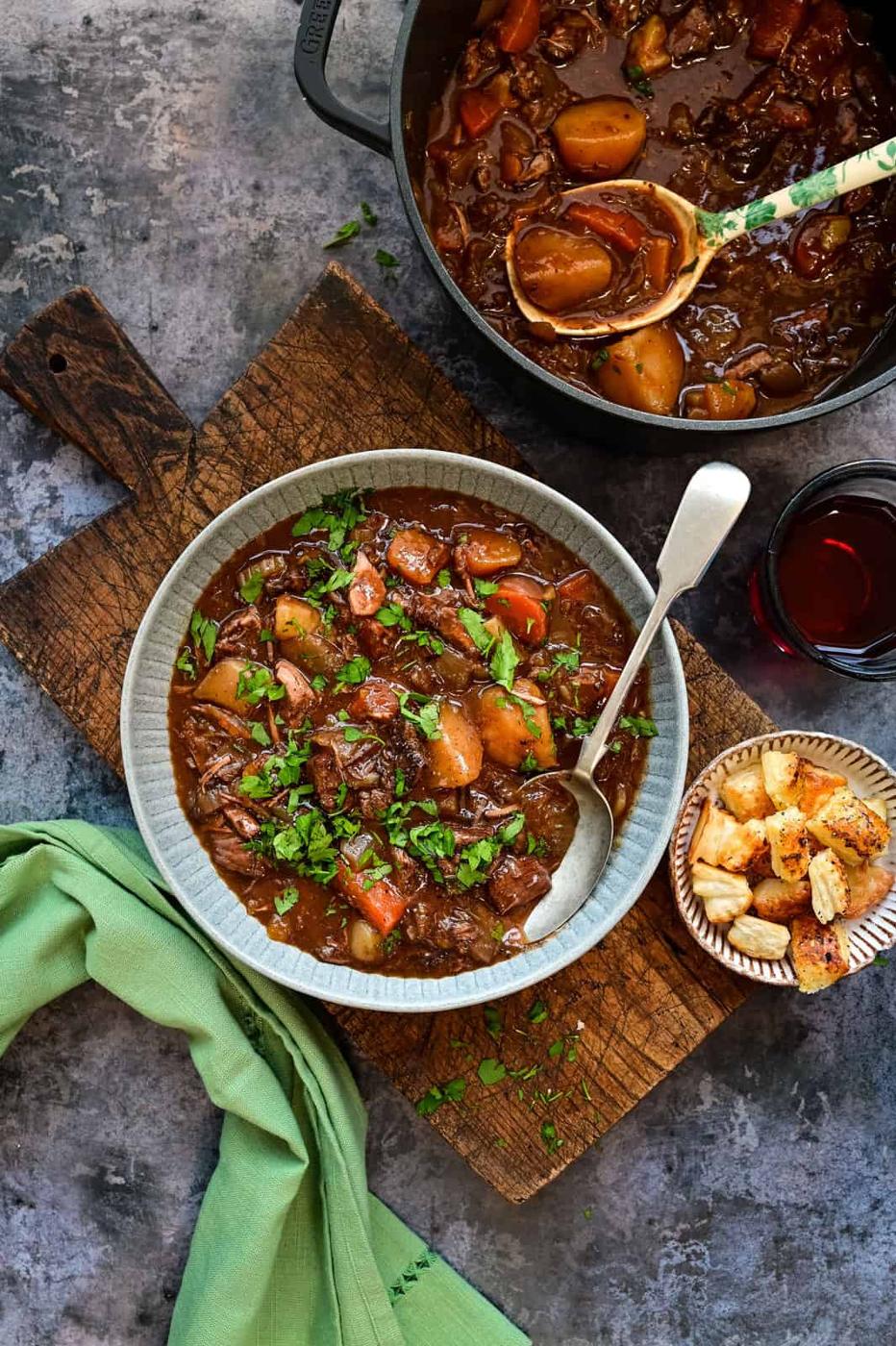 Serving of beef stew in a bowl with Dutch Oven on the side