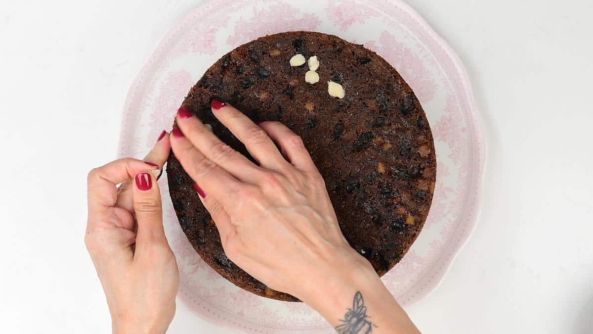 Filling indents on top of fruitcake with small pieces of marzipan to create a flat top