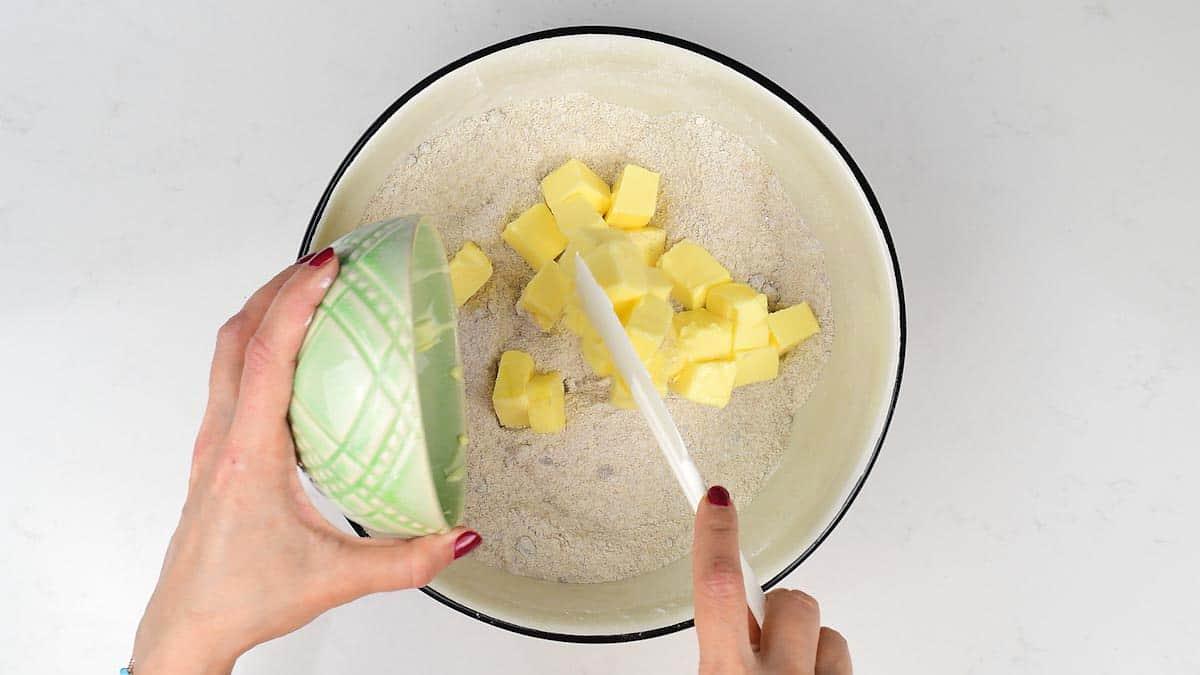 Adding cubed butter to cake ingredients in mixing bowl
