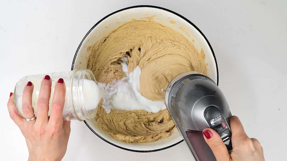 Adding milk to fruitcake batter in a bowl