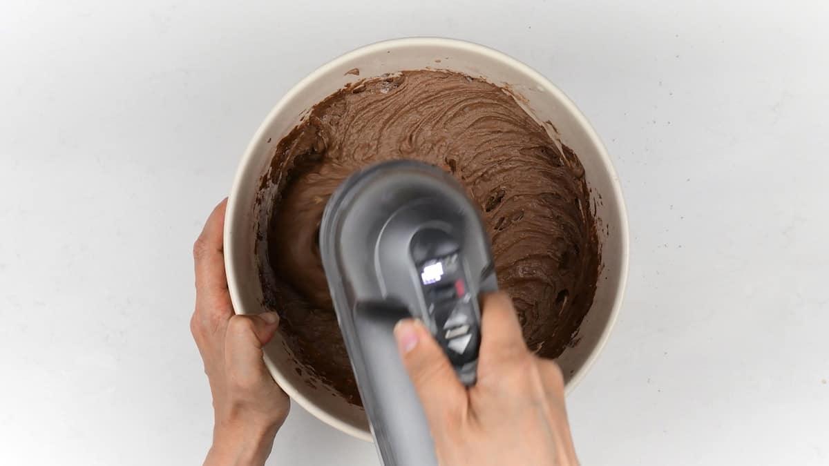 beating chocolate cake batter with an electric hand mixer