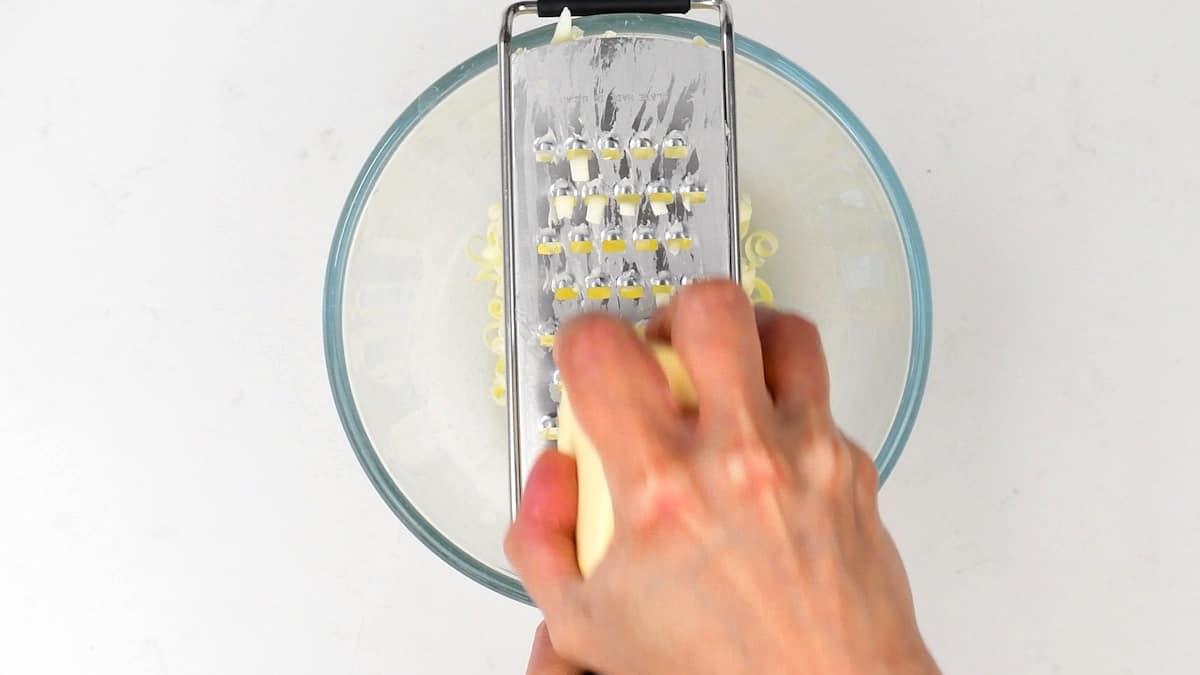 grating frozen butter into a bowl