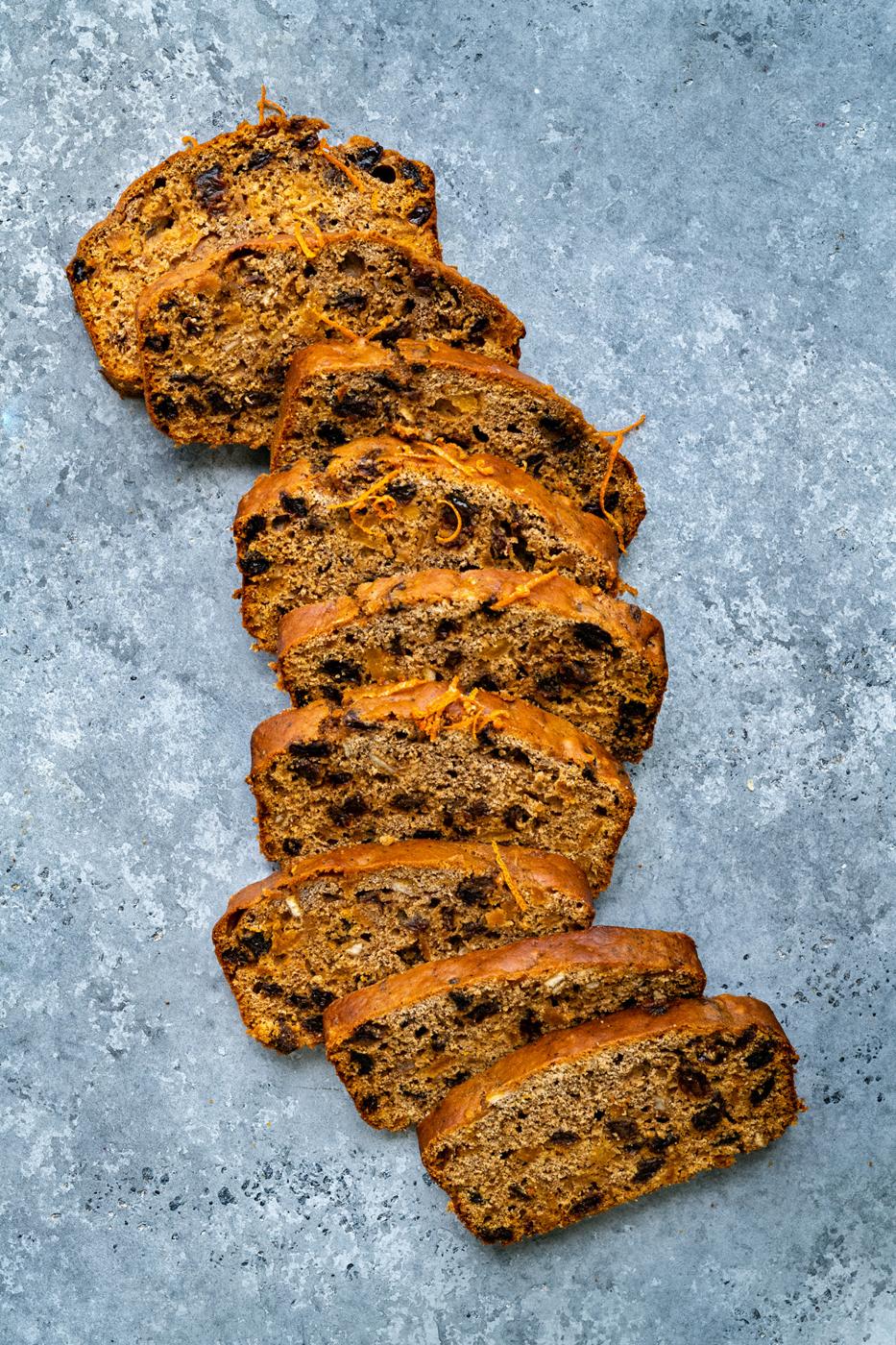 sliced fruit loaf with mixed fruit laid out on a blue background