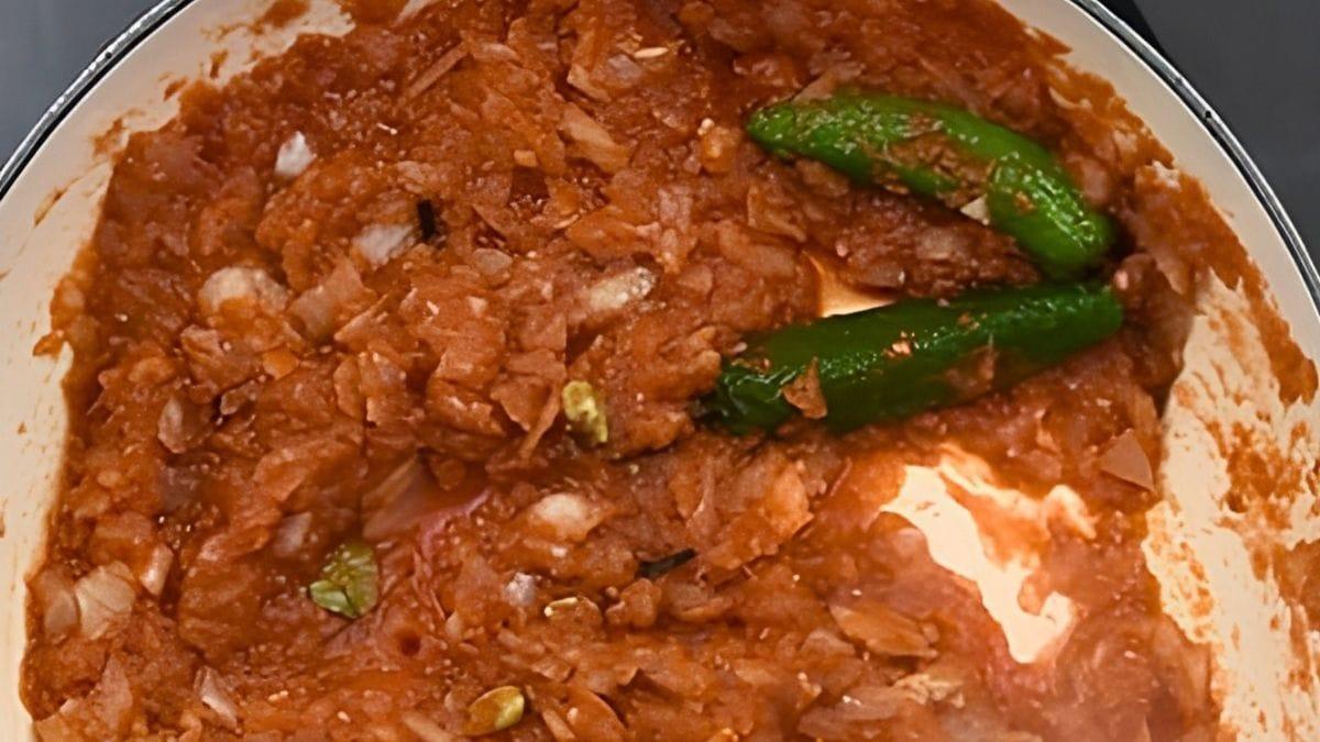 Crushed tomatoes, chopped onions and two whole green chilies in a pot – the start of the bhuna masala.