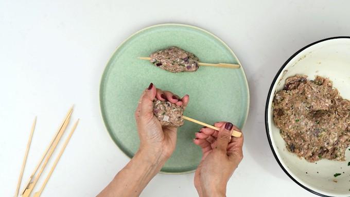 Threading lamb kofta onto bamboo skewers