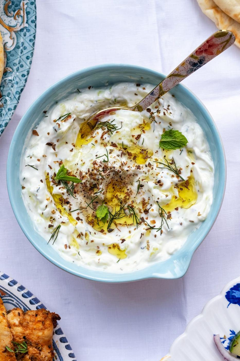 bowl of Greek Tzatziki garnished with fresh herbs and olive oil