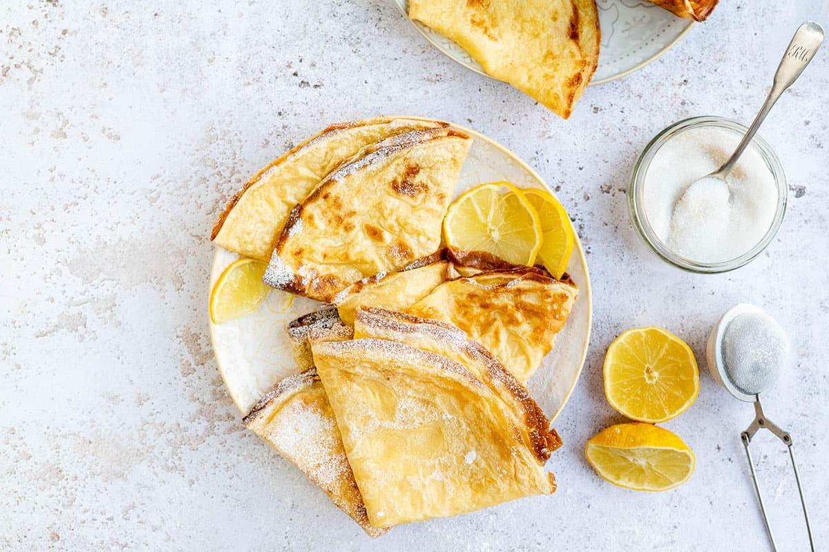 English pancakes served with sugar an lemon on a plate