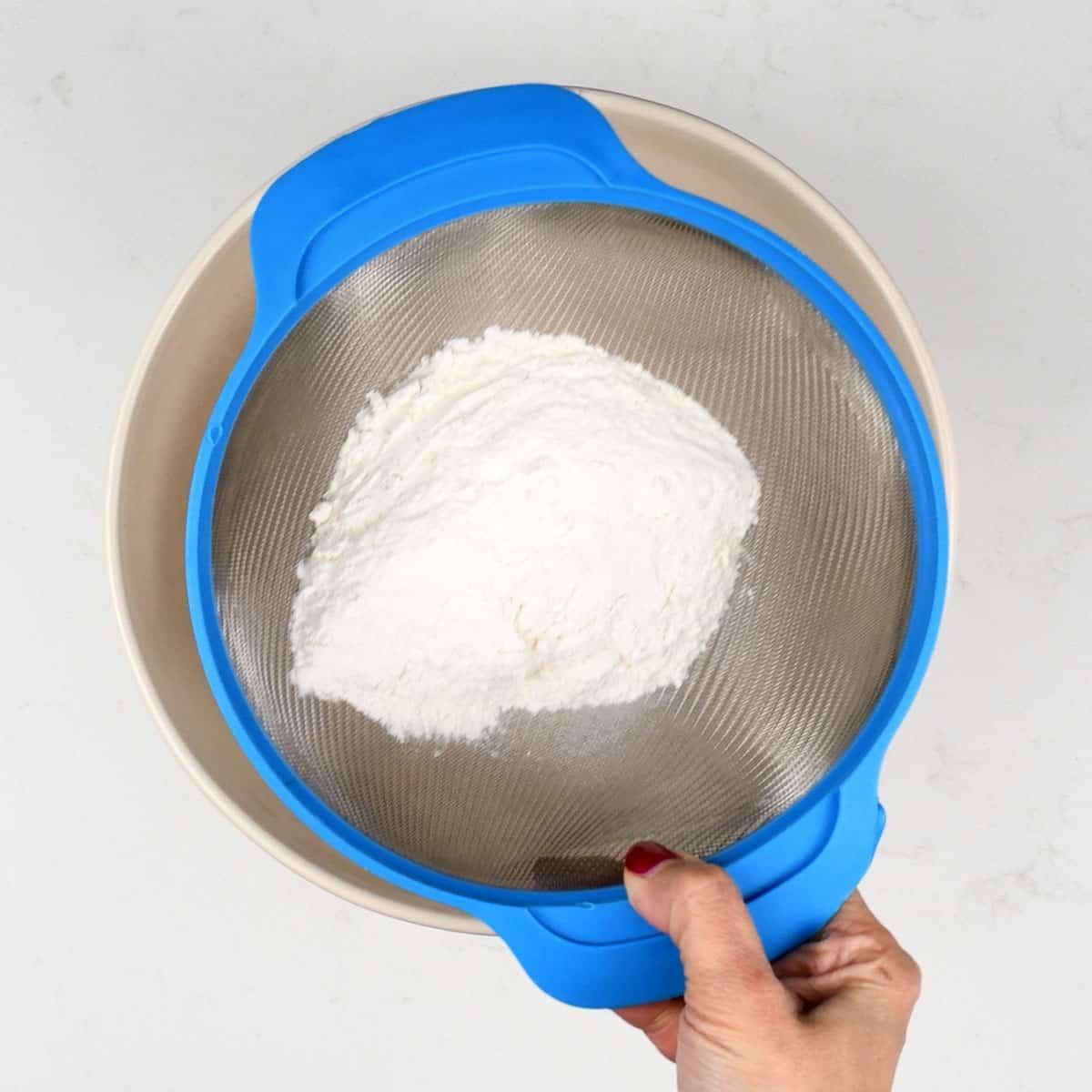 Sifting flour over a bowl