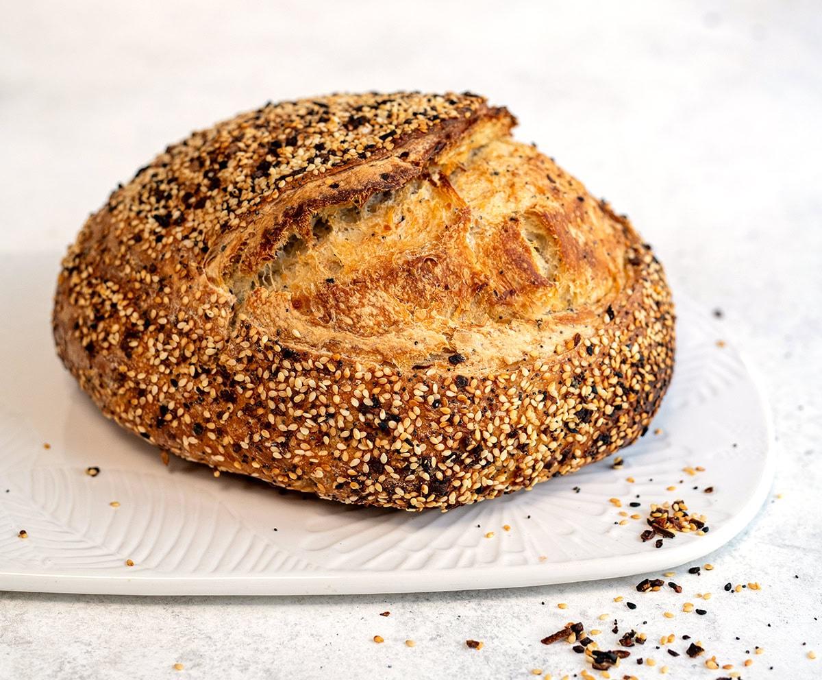 Everything Sourdough (sourdough loaf with everything bagel seasoning) on a ceramic board