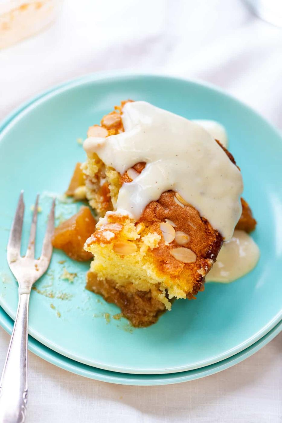 Slice of Apple Sponge served with vanilla custard on an aqua plate