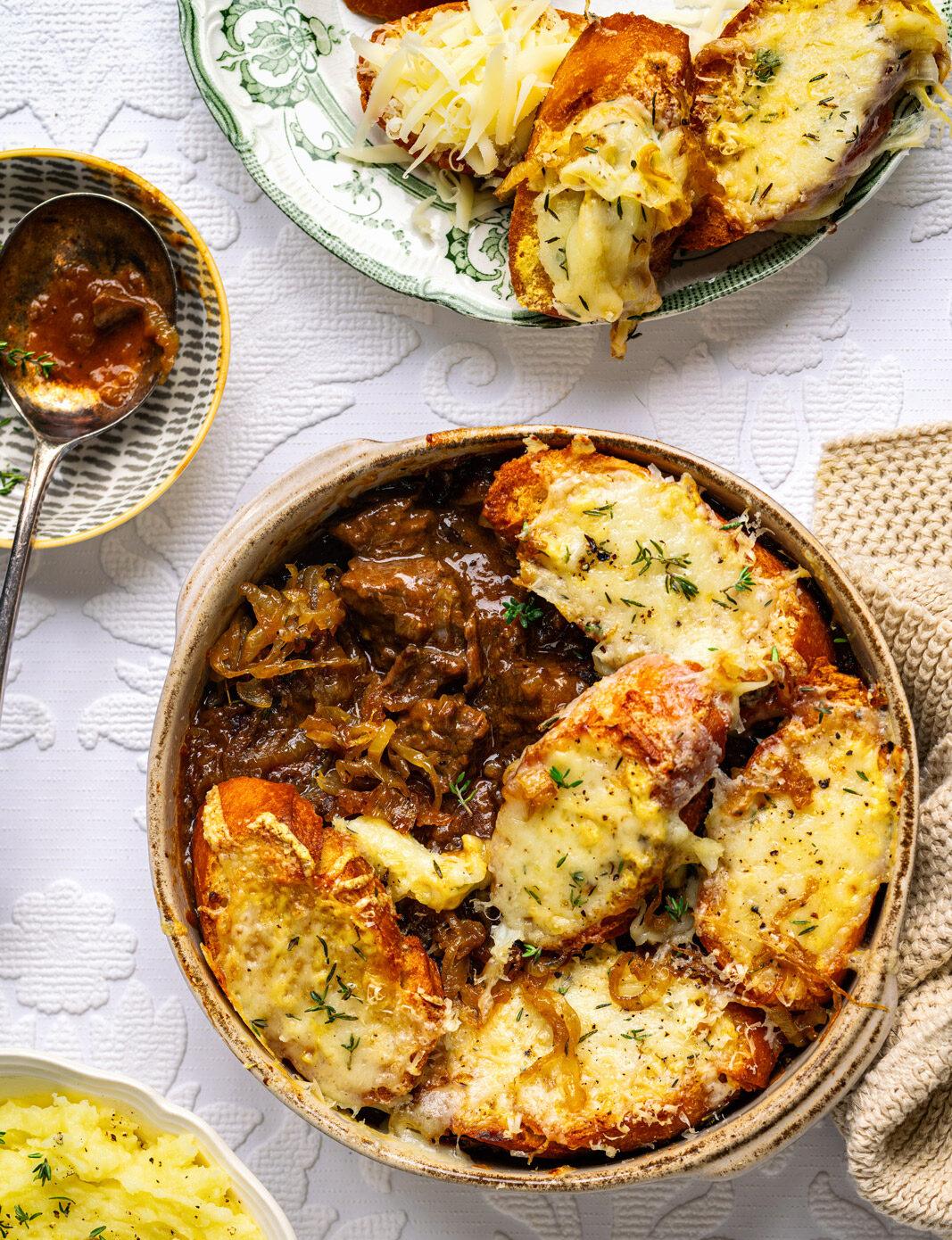 French onion beef stew in a small ceramic dish topped with cheesy croutons