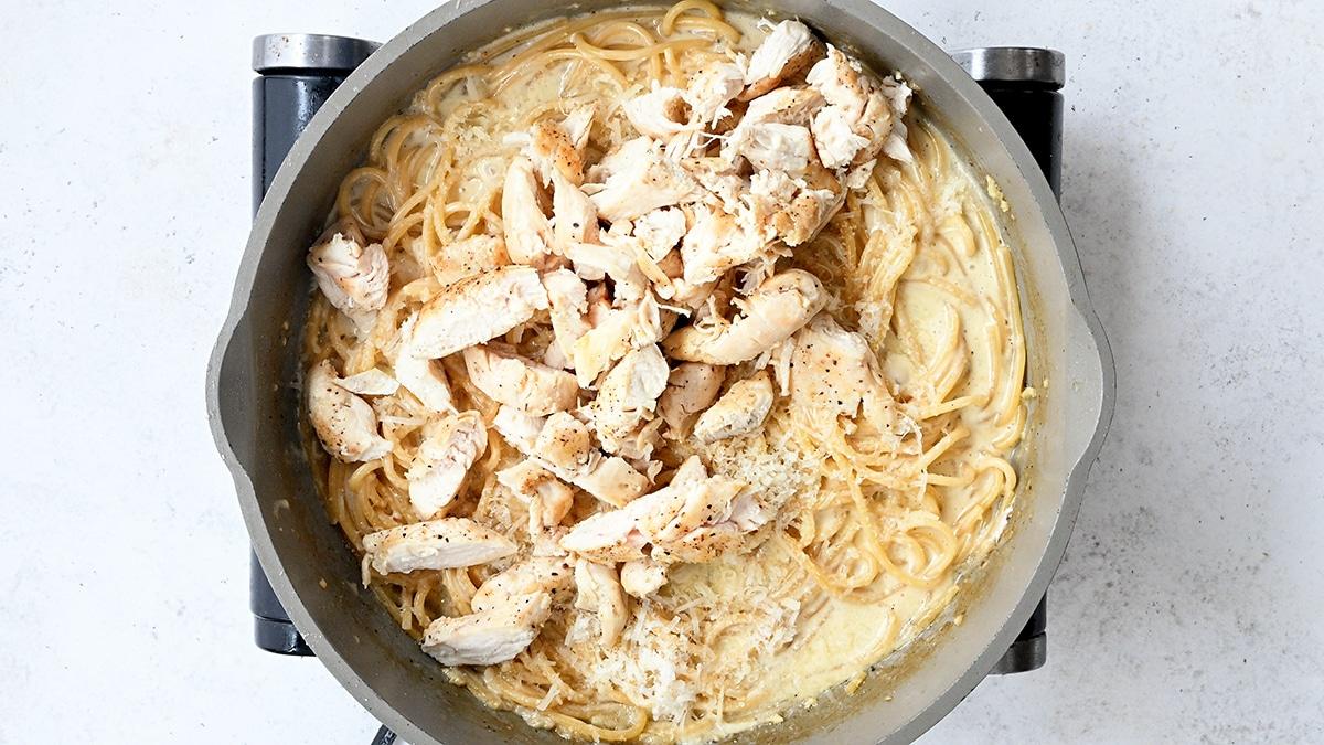 cooked chicken breast in a pan of creamy garlic Parmesan spaghetti