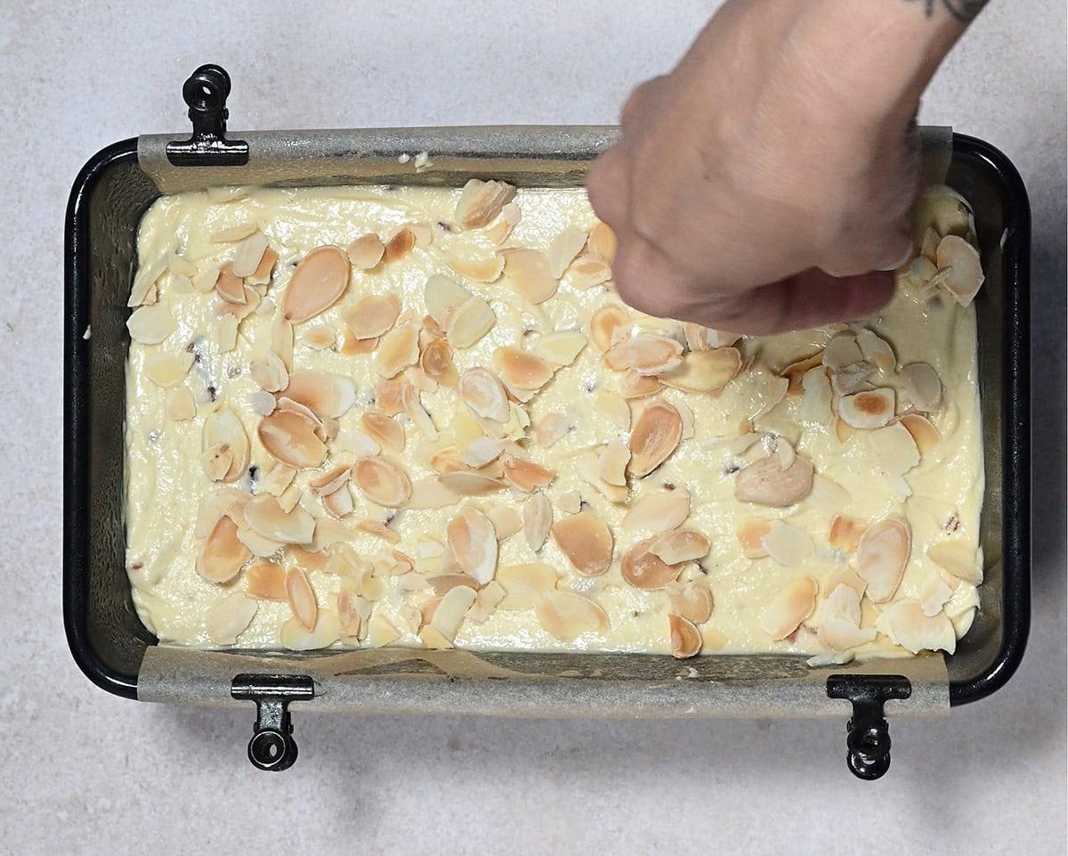 topping a loaf cake with flaked almonds before baking
