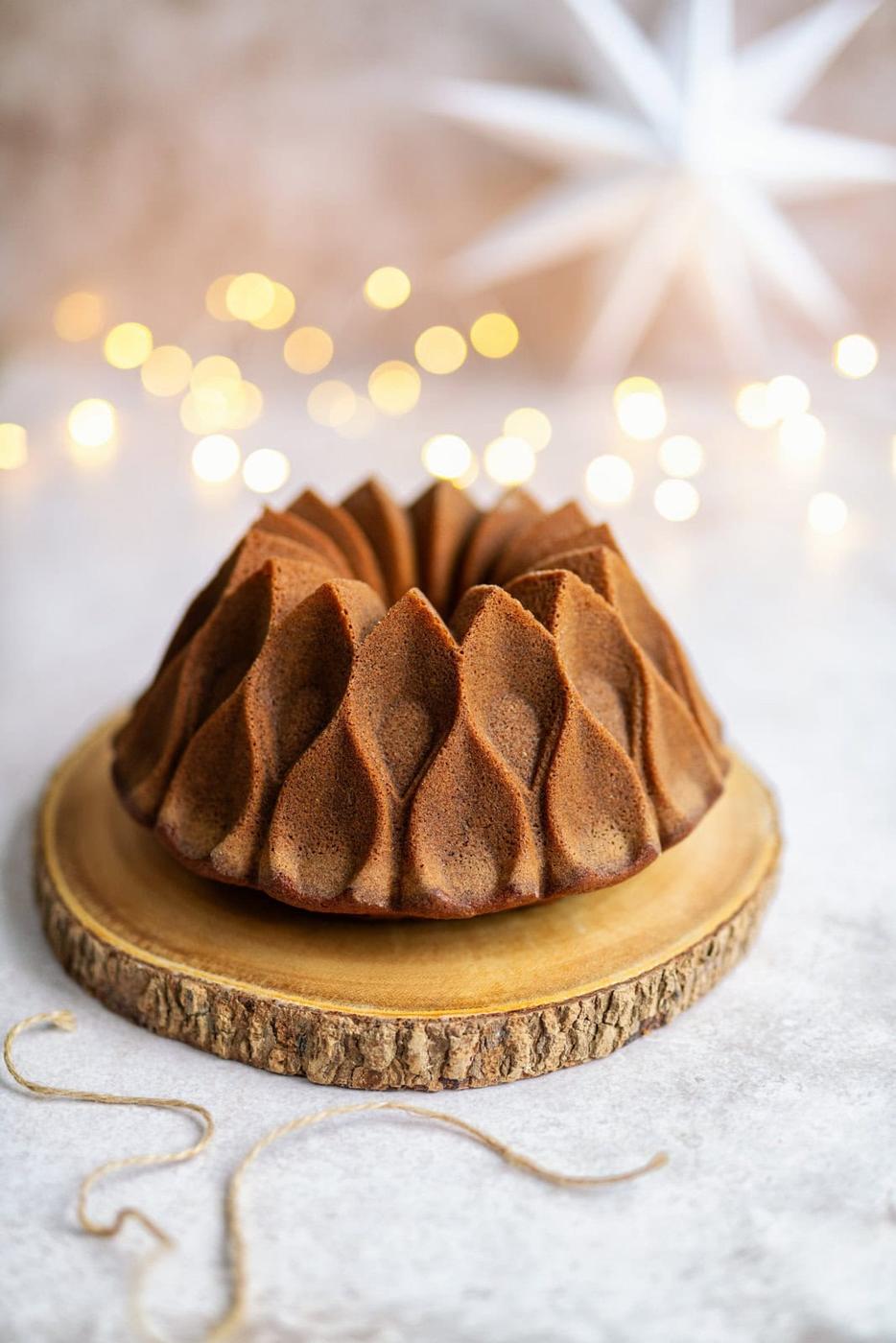 Christmas gingerbread bundt cake on a wooden board, festive decorations in the background