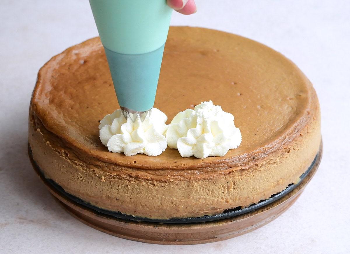 piping whipped cream over cheesecake