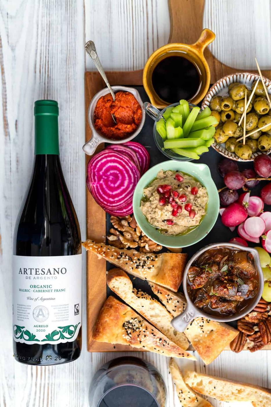 Wine bottle next to board loaded with appetizers