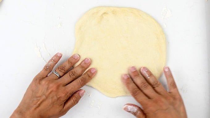 rolling out Greek pita bread