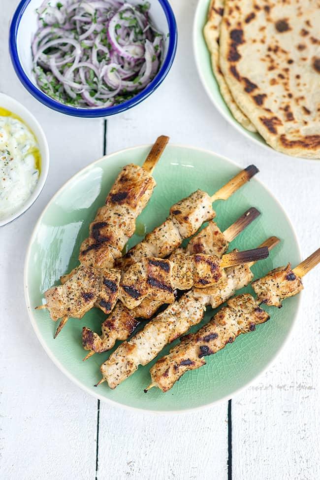 pork souvlaki skewers on a green plate